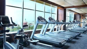 A gym with multiple treadmills and stationary bikes, large windows with a city view. - ibis Balikpapan (Balikpapan)