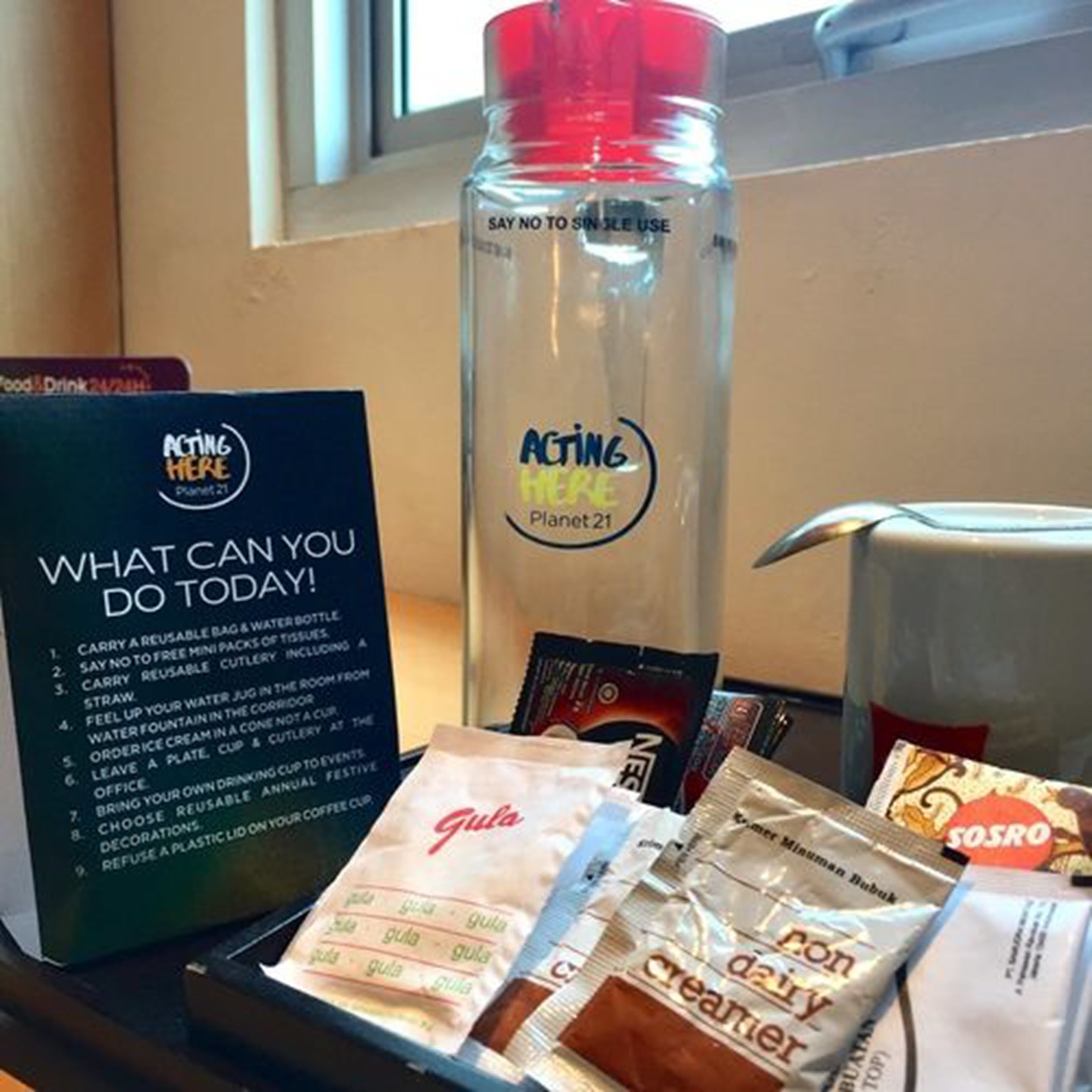 A sign with suggestions for eco-friendly actions, a water bottle, and various food items.
