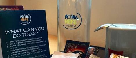A sign with suggestions for eco-friendly actions, a water bottle, and various food items.