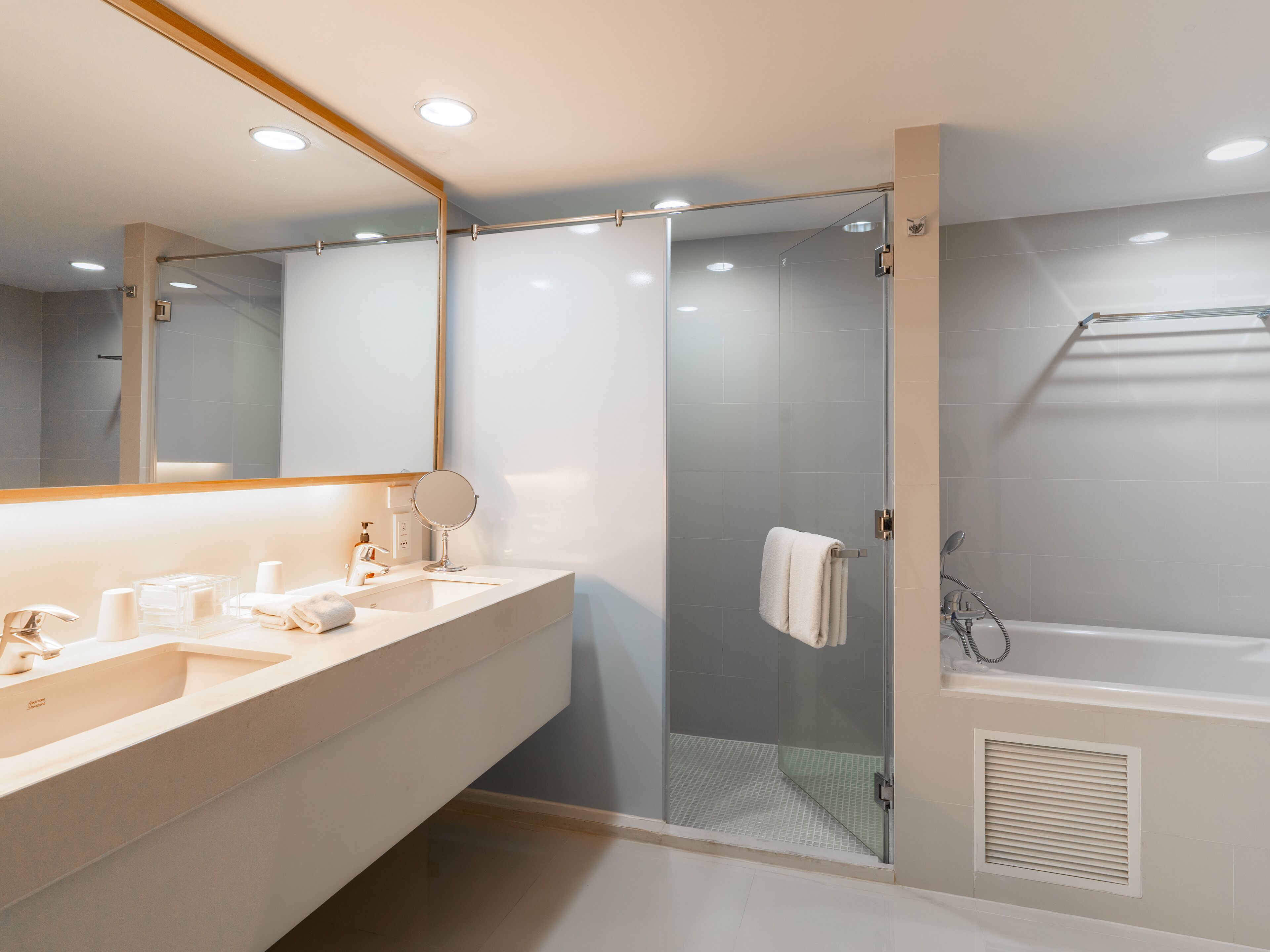 Une salle de bain moderne avec un grand miroir, un lavabo, une douche et une baignoire.