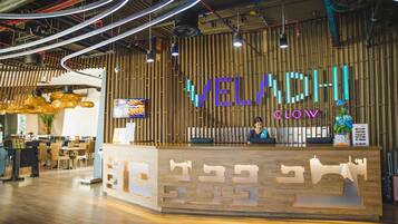 Un mostrador de recepción con un letrero de neón, paneles de madera y un diseño de interiores moderno.