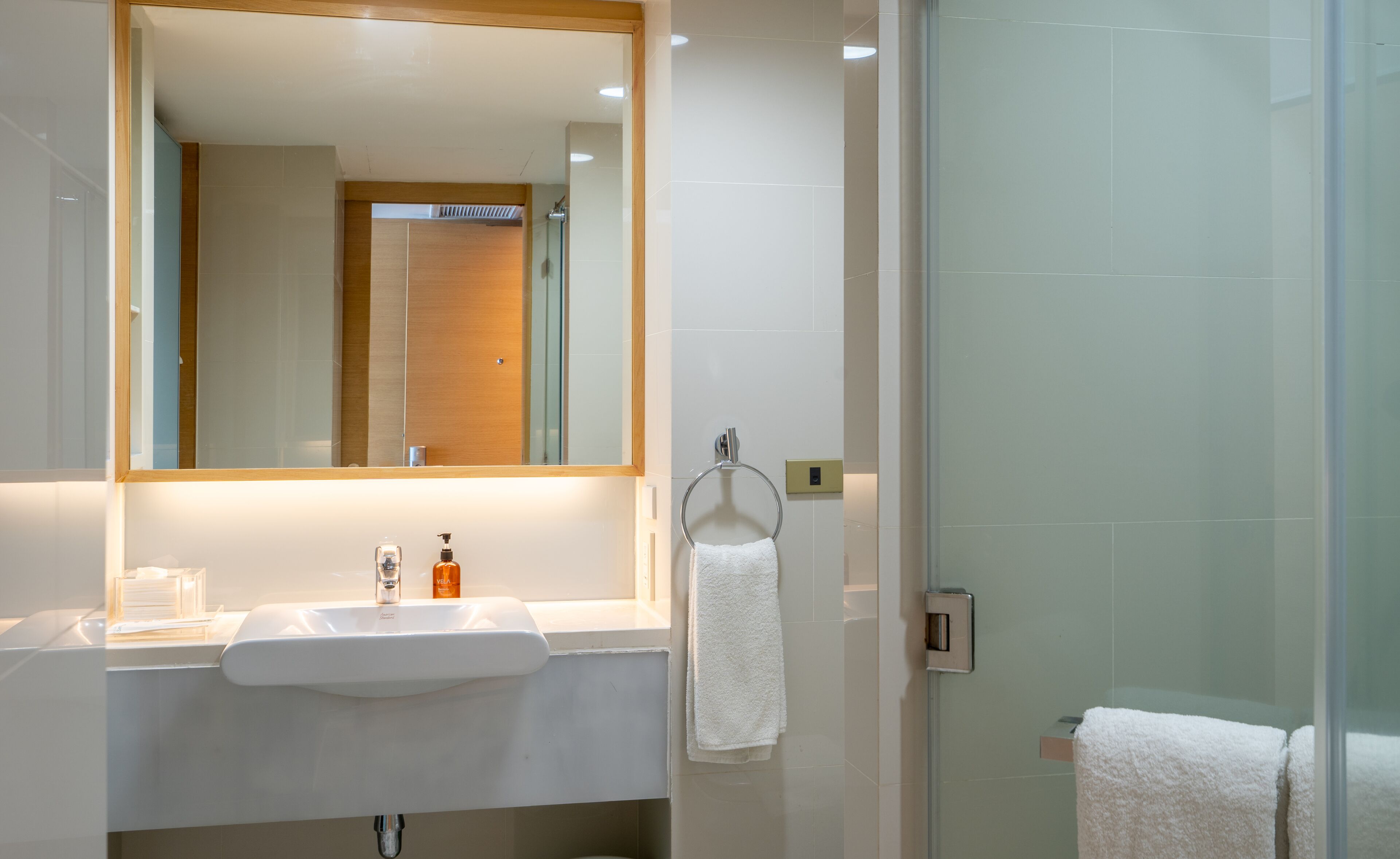 A modern bathroom with a white sink, mirror, and glass shower enclosure.