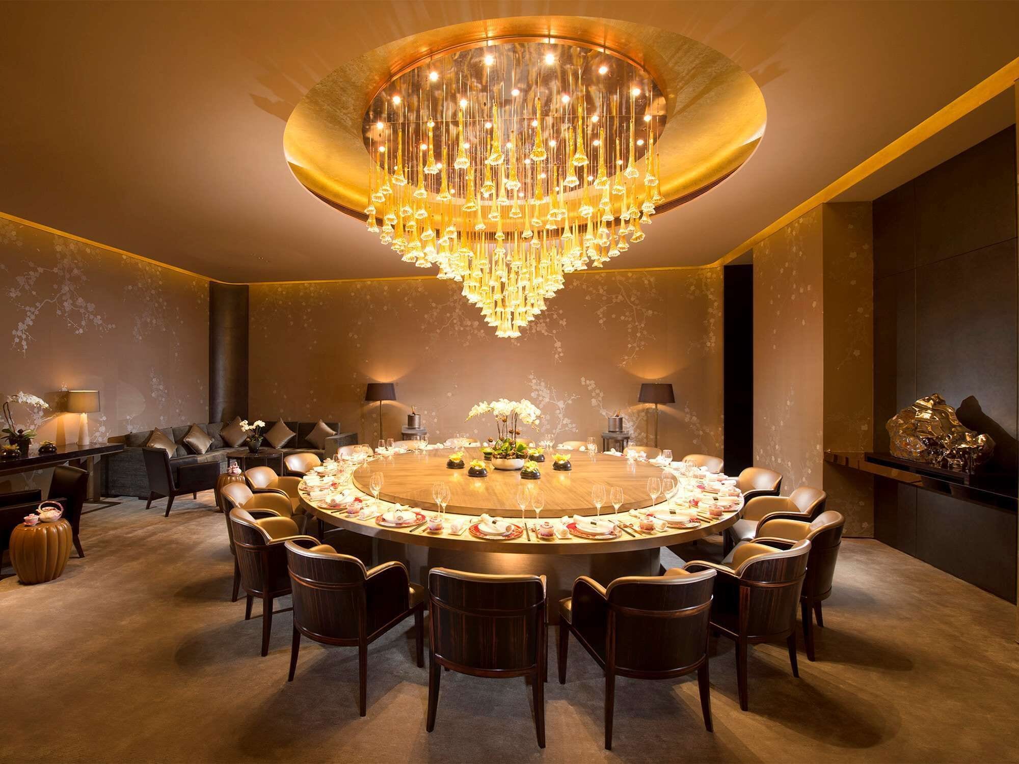 Una sala da pranzo lussuosa con un tavolo rotondo, eleganti sedie e un sontuoso lampadario.