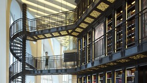 A spacious library with a central spiral staircase, multiple seating areas, and large windows allowing natural light. - Conrad Beijing (Beijing)
