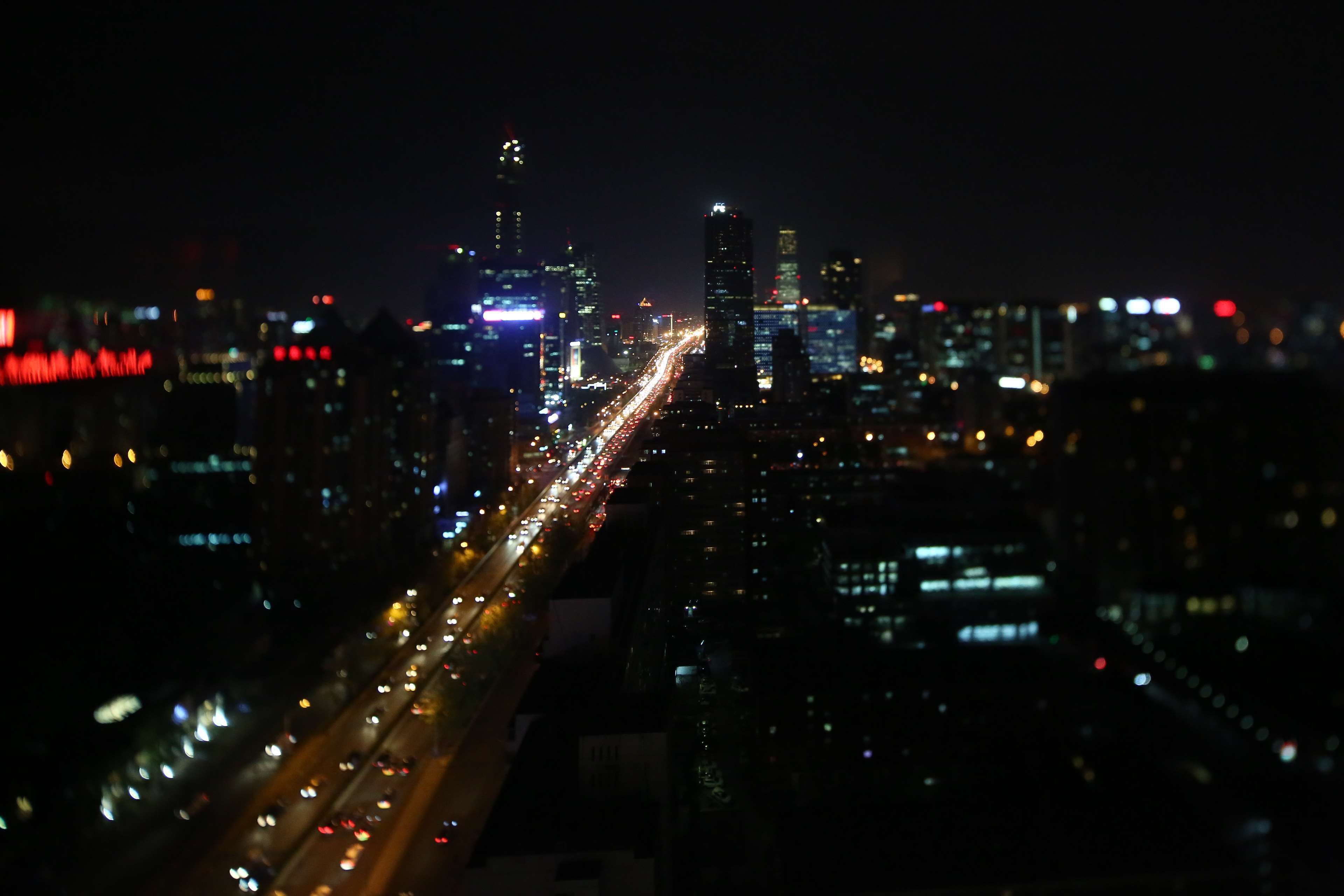 A nighttime cityscape with a busy highway and illuminated buildings.