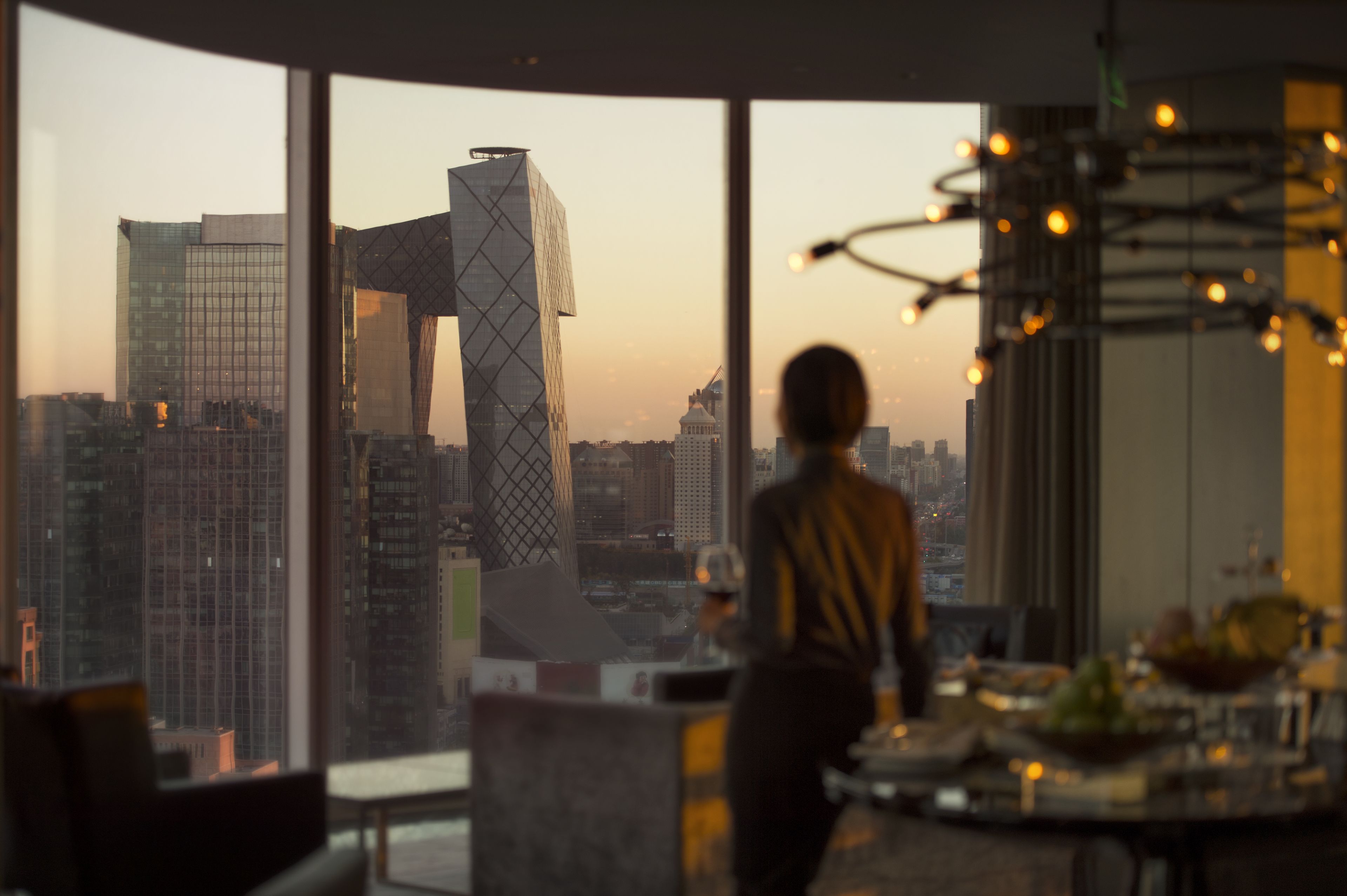 A modern interior with large windows offering a cityscape view, including a distinctive building with a unique design.