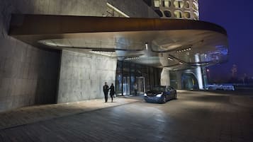 Un bâtiment moderne avec une entrée incurvée et une voiture garée devant.