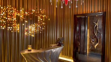 A modern interior with a metallic wall, a red chandelier, and a unique door design.