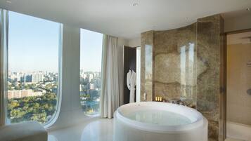 A modern bathroom with a large bathtub, a glass shower enclosure, and a view of a cityscape.