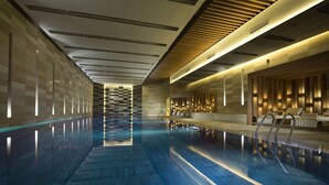 A modern indoor swimming pool with a clear water surface, a long, narrow design, and a wooden ceiling with integrated lighting. - Conrad Beijing (Beijing)