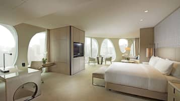 Habitación de hotel moderna con una cama grande, un escritorio y una zona de estar con vistas a la ciudad.