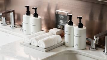 A bathroom with a marble countertop, a sink, and a towel rack. There are bottles of toiletries and a clear plastic bottle with a label.