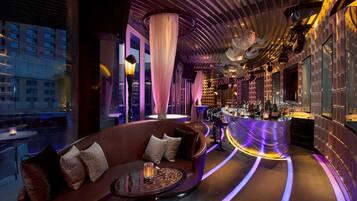 Eine moderne Bar mit gebogener Bar, Sitzgelegenheiten und Blick auf die Skyline.