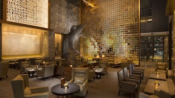 A spacious lobby with modern furnishings, a large abstract sculpture, and a patterned wall.