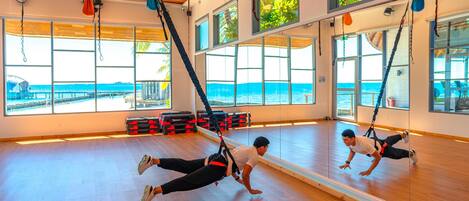 A gym with large windows, wooden floors, and exercise equipment.