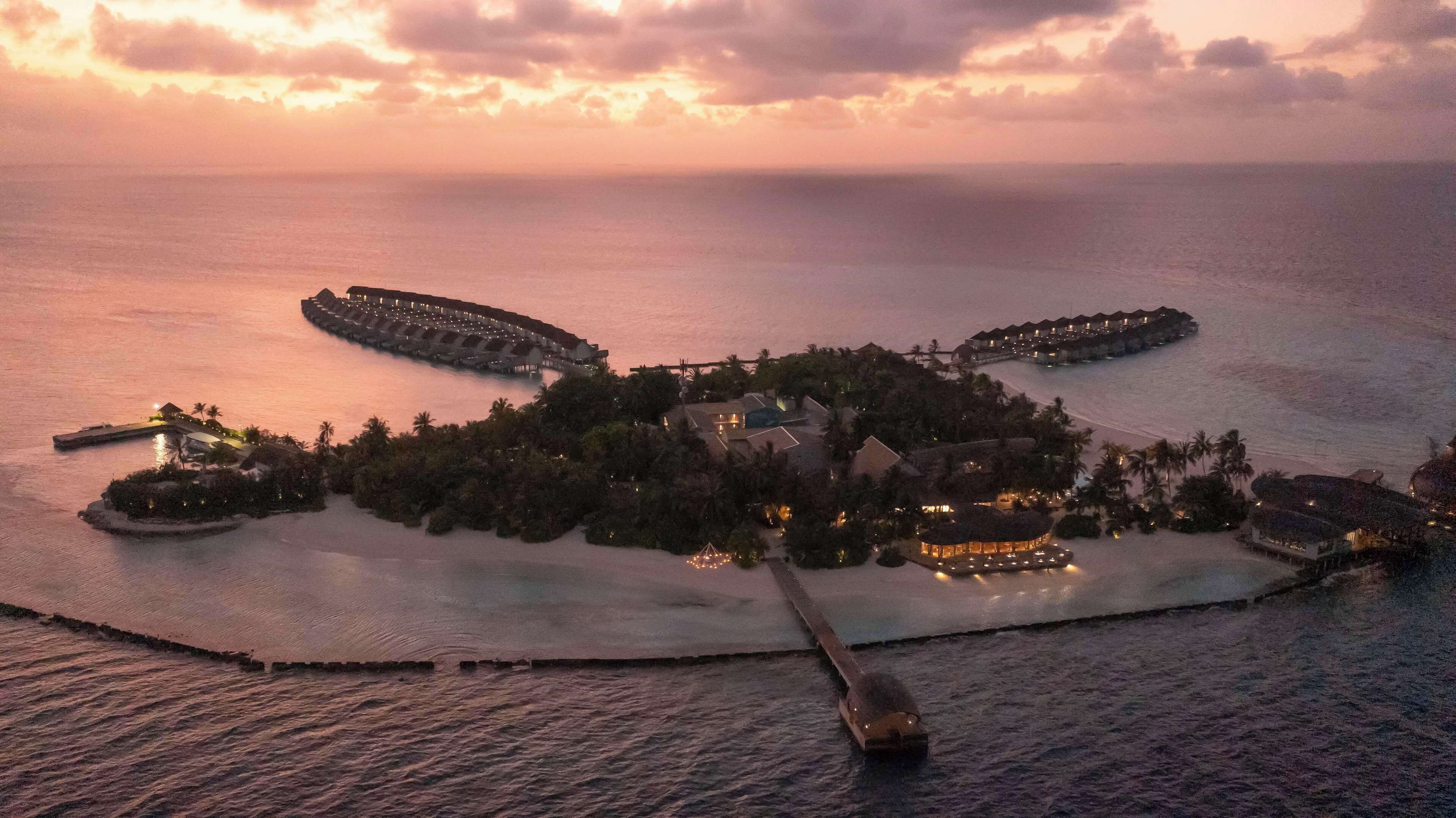 A resort island with multiple overwater bungalows, a central building, and a pier.