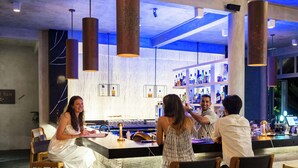 A bar area with wooden chairs, a bar counter, and hanging pendant lights.