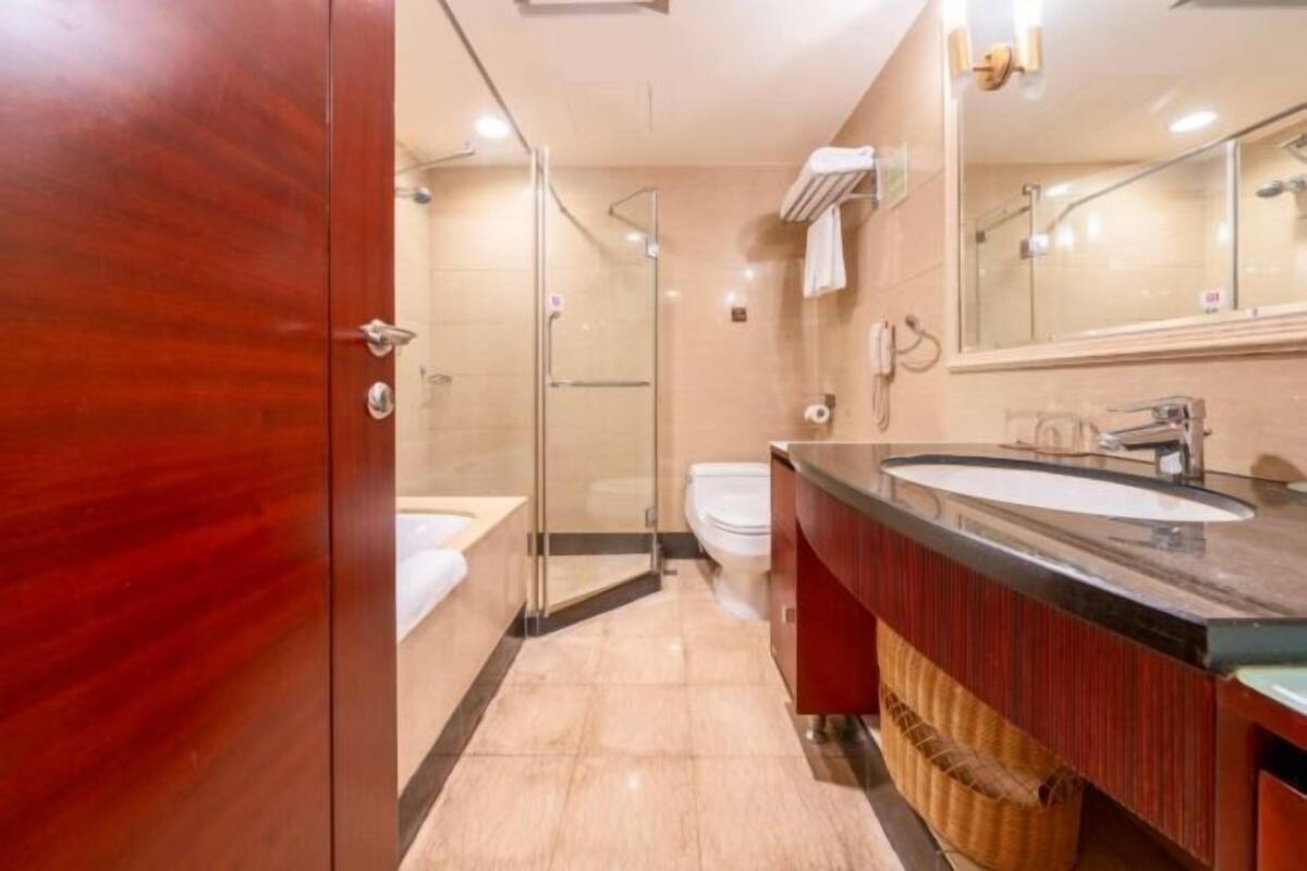Une salle de bain moderne avec une douche à parois de verre, des toilettes blanches et un meuble-lavabo avec un miroir.