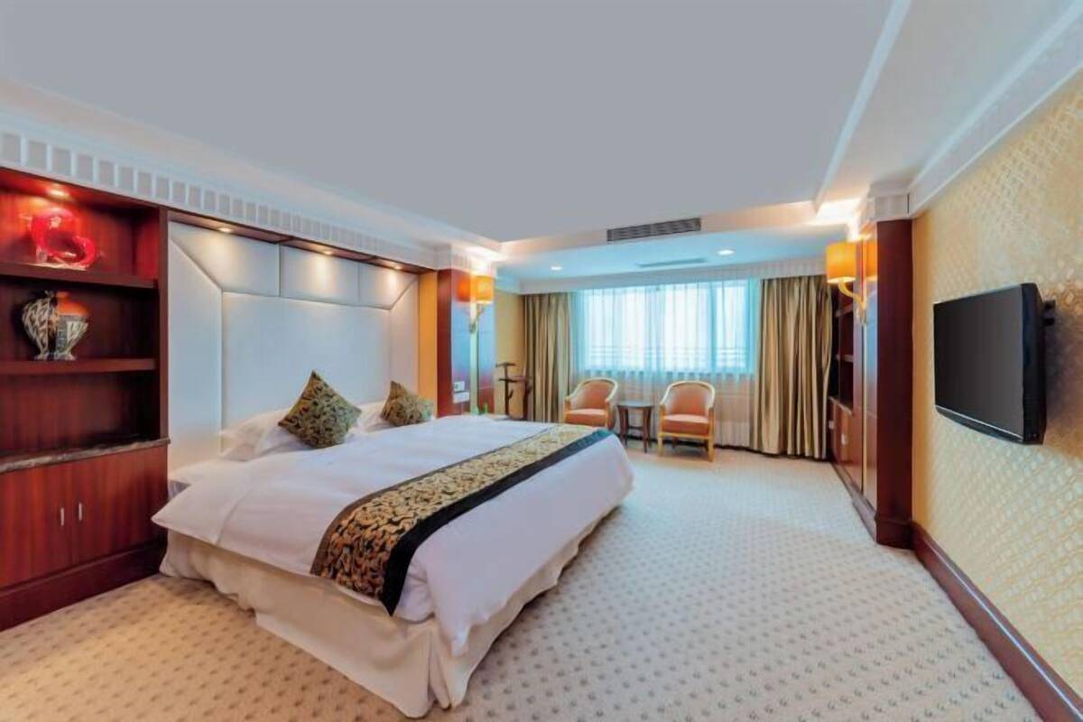 Une chambre d’hôtel avec un grand lit, une télévision, un bureau et une chaise.
