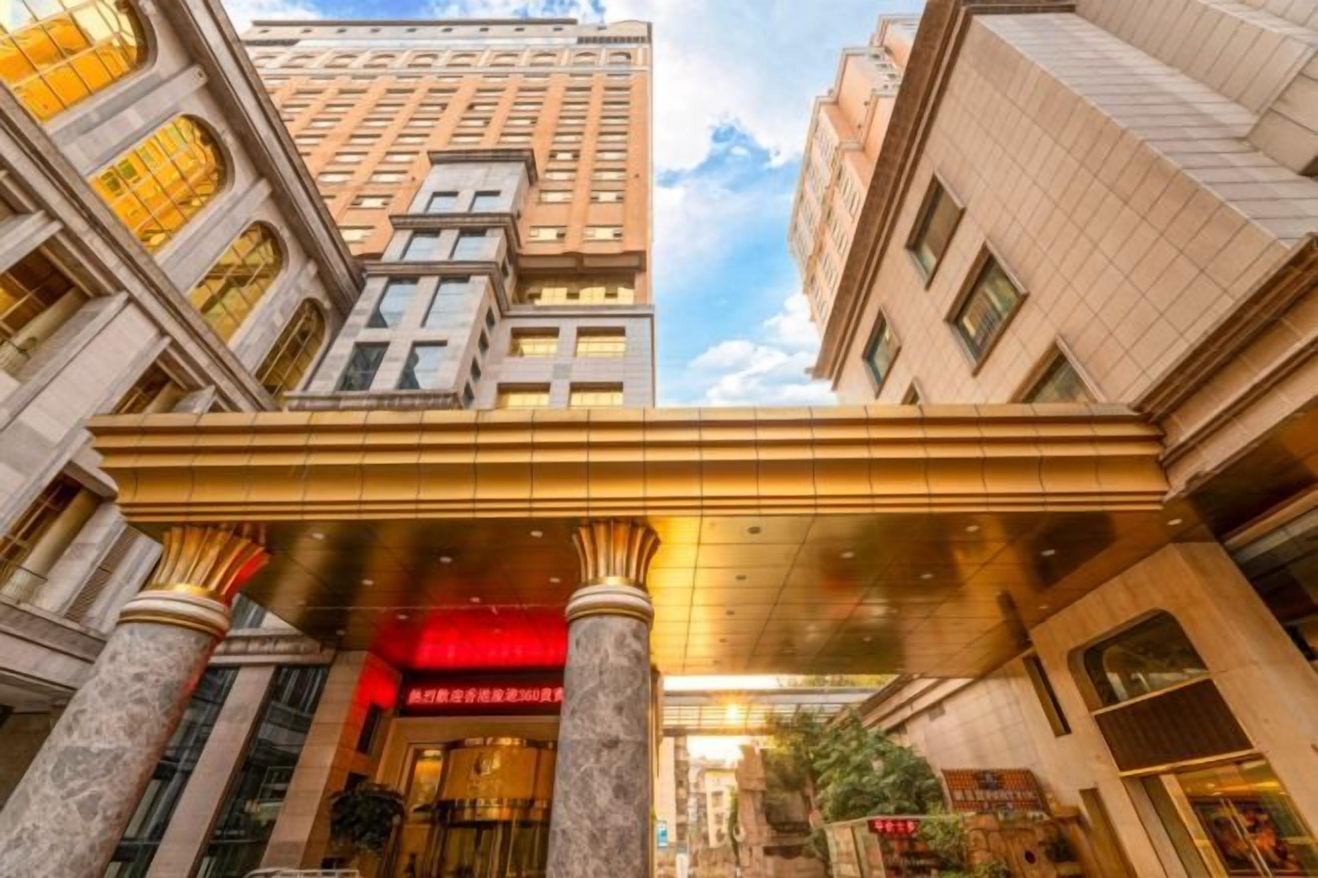 A hotel entrance with a red sign, large columns, and a covered walkway.
