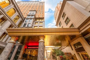 A hotel entrance with a red sign, large columns, and a covered walkway. - Hotel de Royce (Shaoguan)
