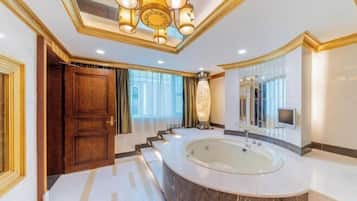 Un baño lujoso con una bañera grande, un espejo y una araña.