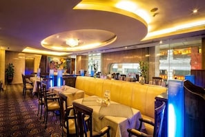 A restaurant with a curved ceiling, round tables, and a bar area. - Hotel de Royce (Shaoguan)