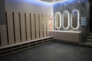 Un baño moderno con un banco de madera, un tocador con espejo y una pared de mármol.