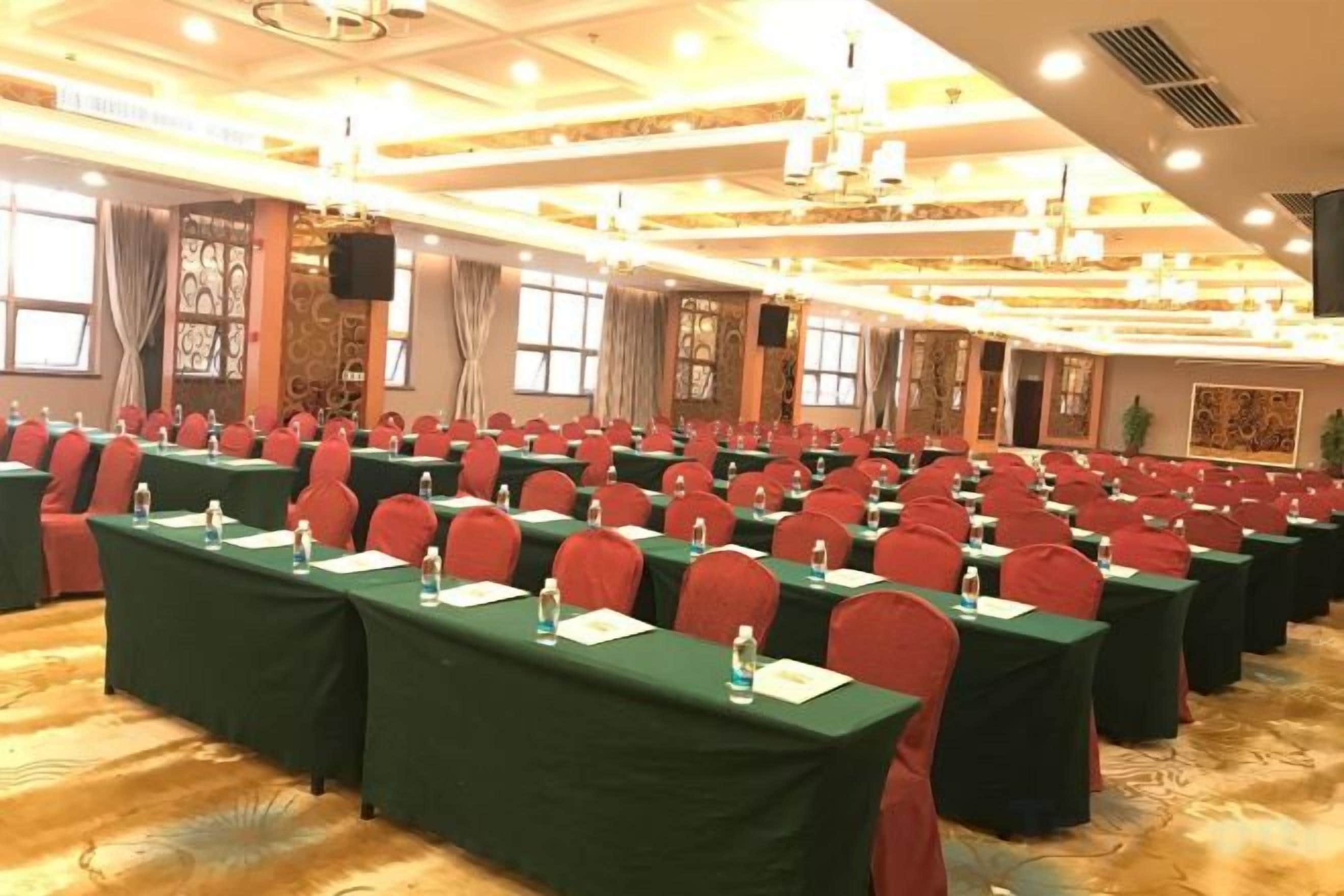 Une salle de conférence avec des rangées de tables et de chaises, équipée de plaques nominatives et de bouteilles d’eau.