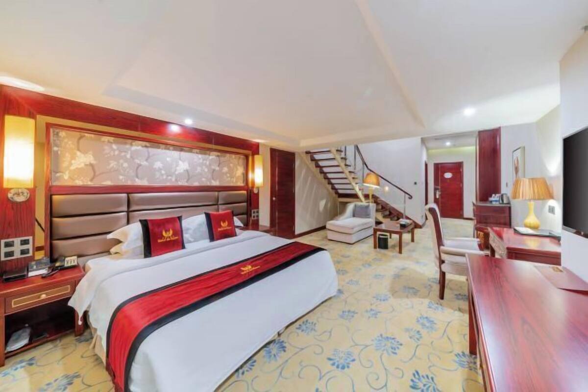 Une chambre d’hôtel avec un grand lit, un bureau, une chaise, un escalier et un téléviseur.