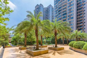 A courtyard with palm trees and a view of high-rise buildings. - Hotel de Royce (Shaoguan)