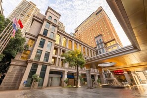 A multi-story hotel with a classical architectural style, featuring a central courtyard with a fountain and a large entrance. - Hotel de Royce (Shaoguan)