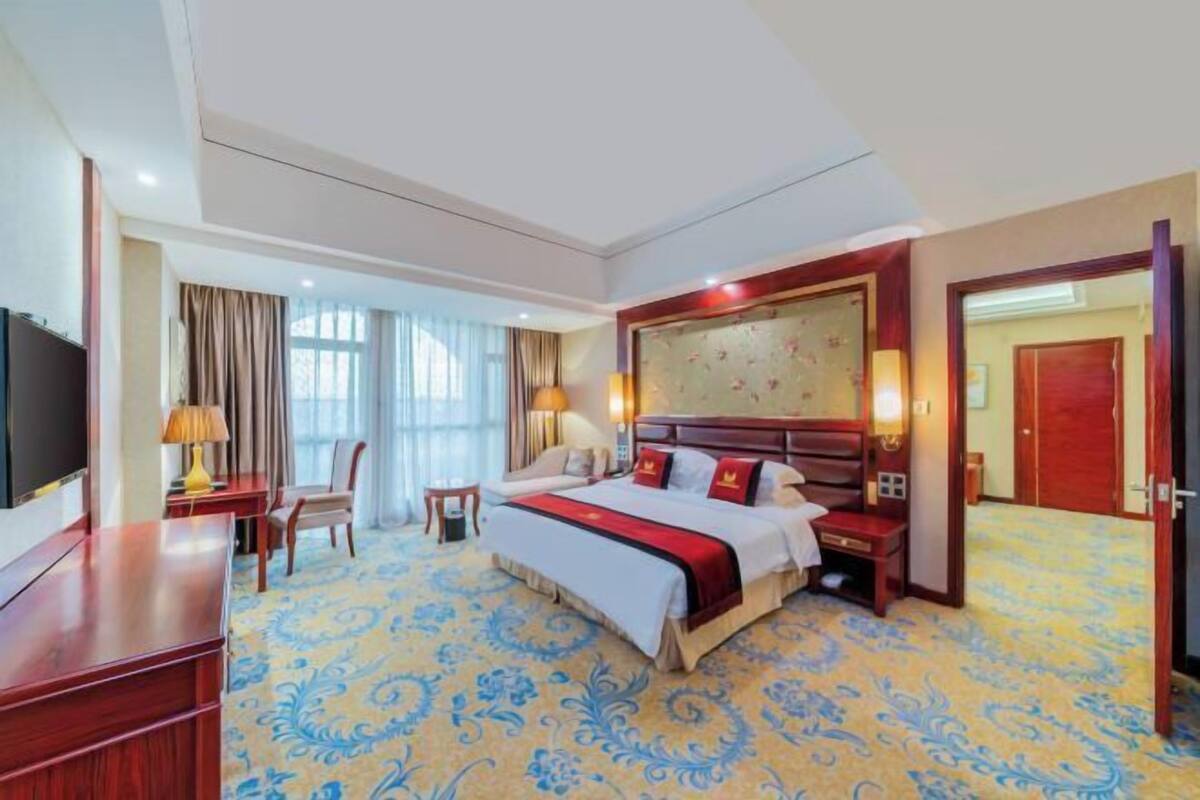 Une chambre d’hôtel avec un grand lit, un bureau, une chaise et un téléviseur.