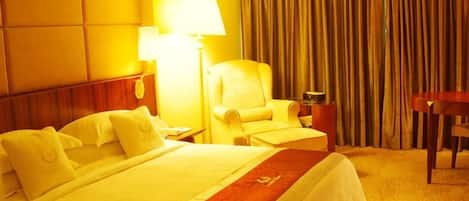 Una habitación de hotel con una cama, una silla, un escritorio y una lámpara.
