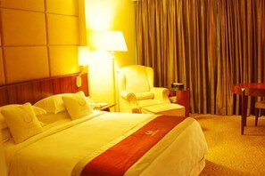 Una habitación de hotel con una cama, una silla, un escritorio y una lámpara.