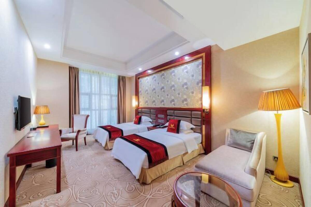 Une chambre d’hôtel avec deux lits, un bureau, une chaise, un canapé et une télévision.