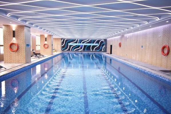 Una piscina de diseño moderno, rodeada de muros con un patrón ondulado y equipada con elementos de seguridad.