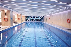 Una piscina de diseño moderno, rodeada de muros con un patrón ondulado y equipada con elementos de seguridad.