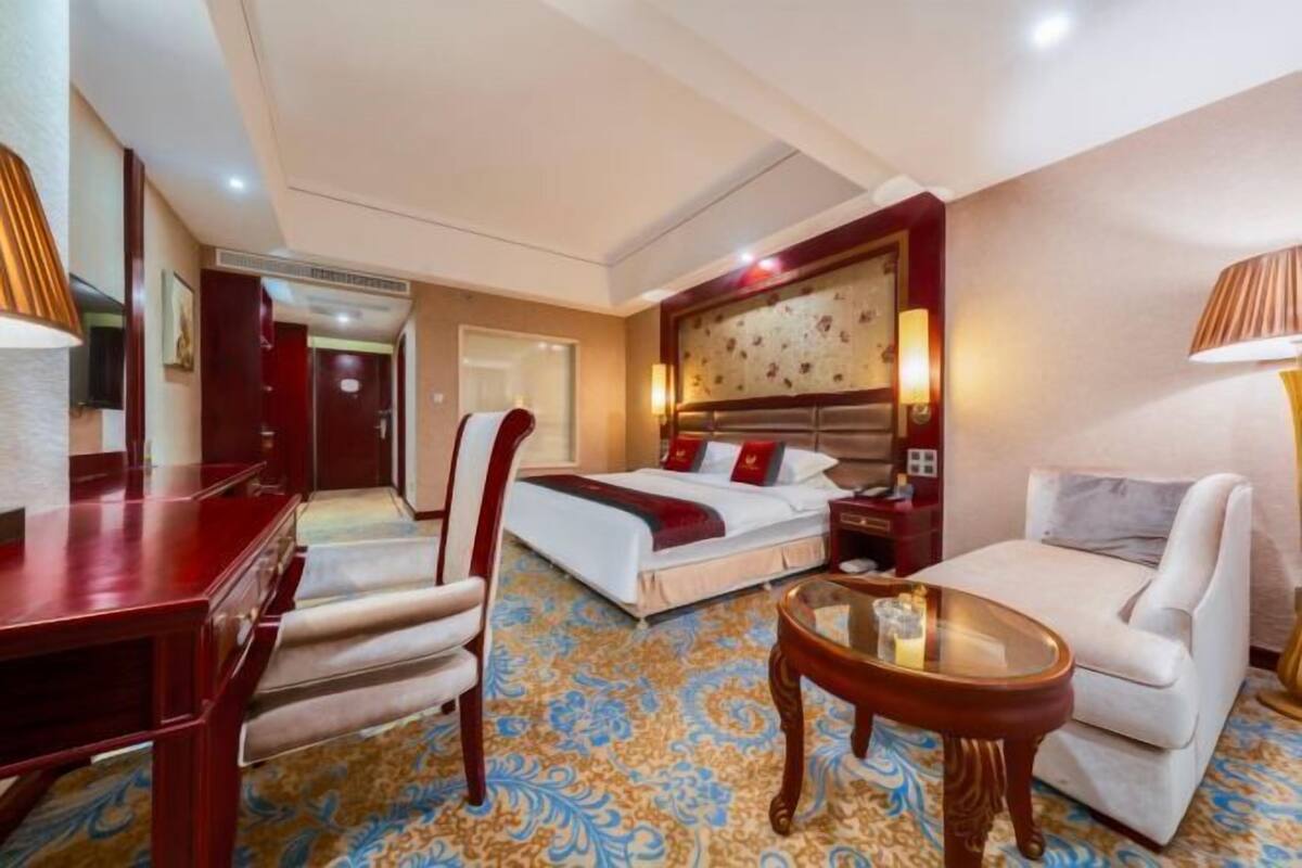 Une chambre d’hôtel avec un lit, un canapé, un bureau et une chaise.