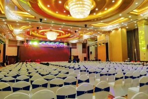 A large hall with rows of chairs, a stage, and a chandelier. - Hotel de Royce (Shaoguan)