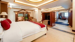 Quarto de hotel com cama grande, armário de madeira, escrivaninha e vista para o exterior.