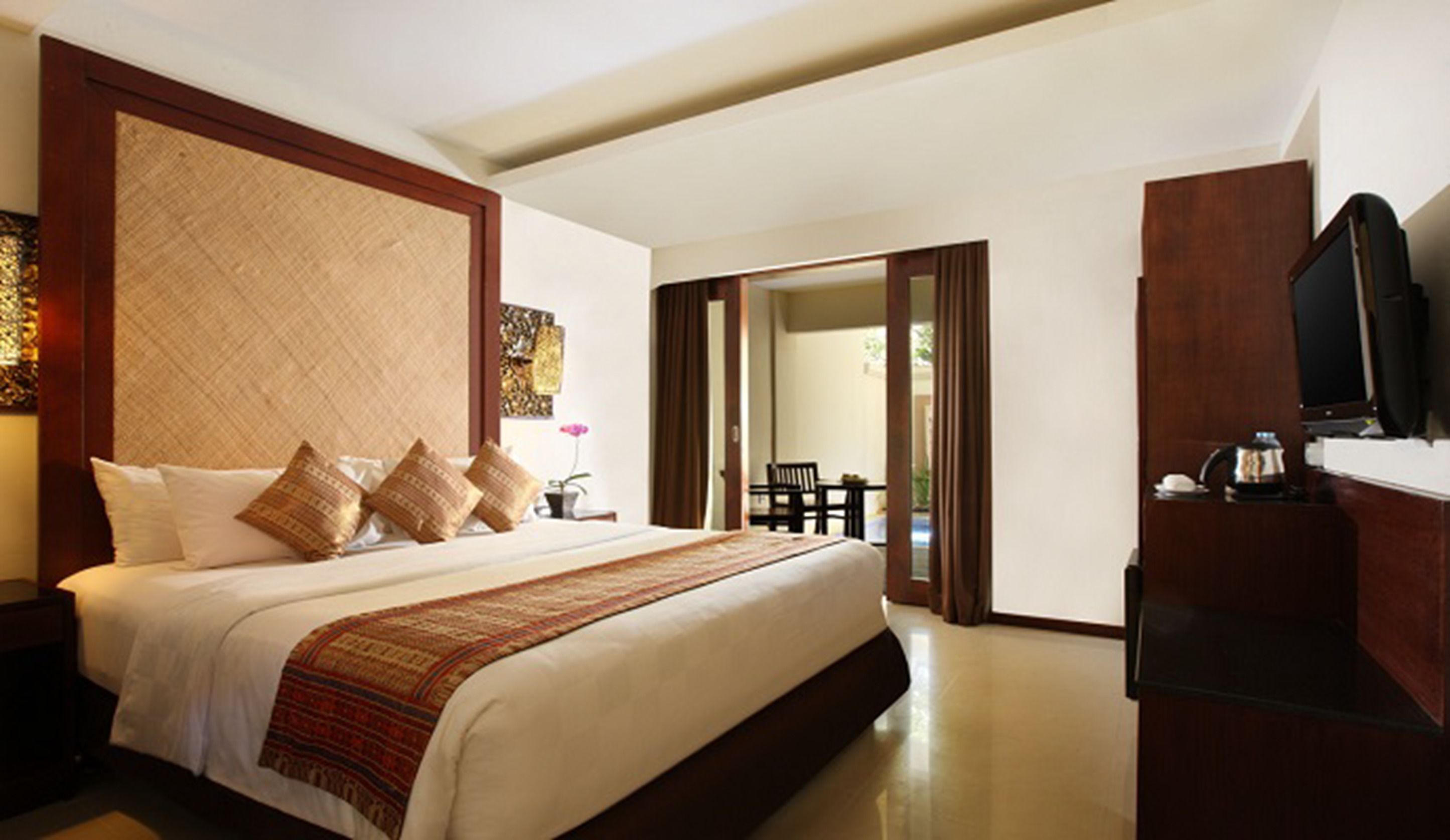 A spacious bedroom with a large bed, a television, and a desk area.