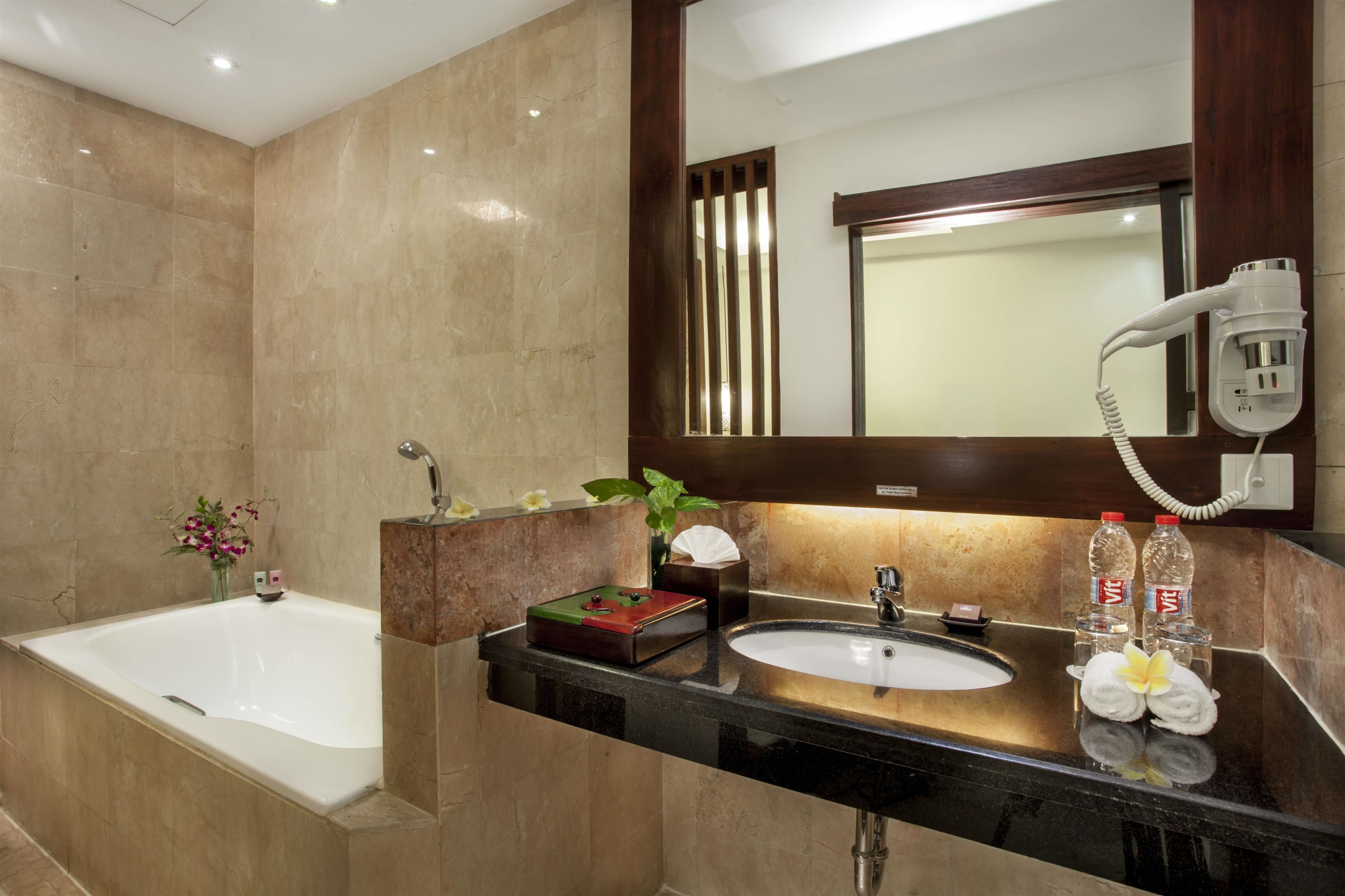 A modern bathroom with a bathtub, a sink, and a hairdryer mounted on the wall.