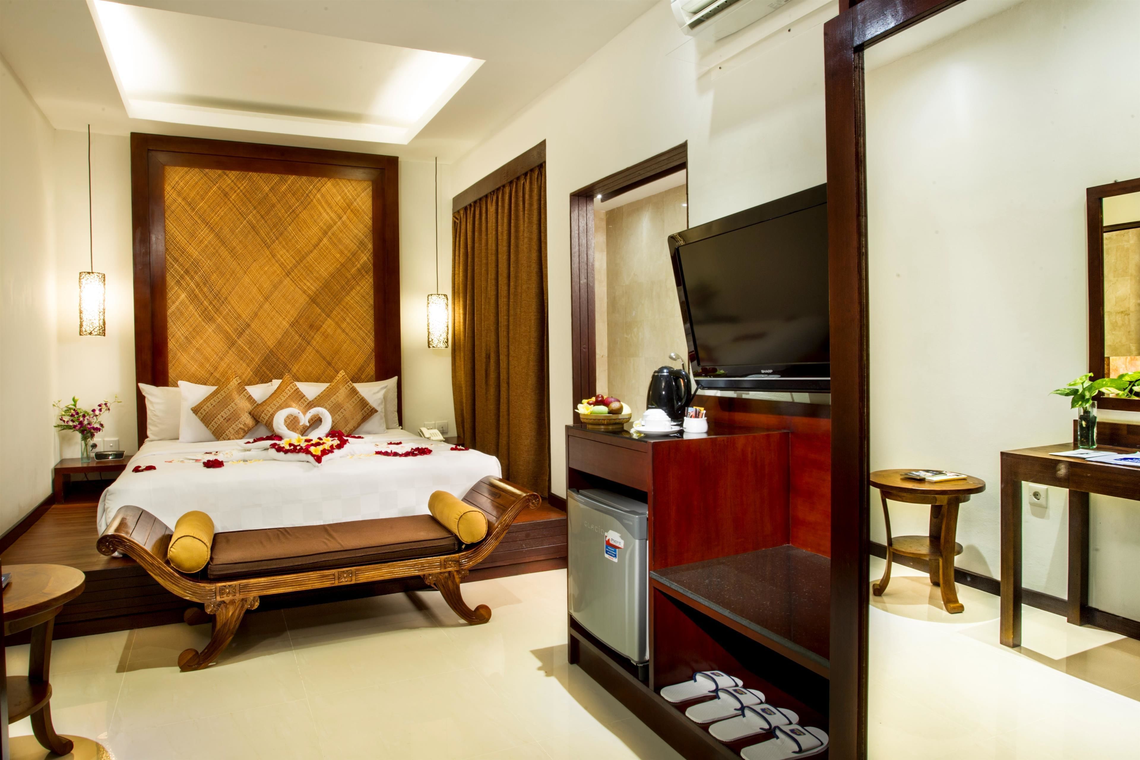 A hotel room with a bed, a television, a desk, and a small table.