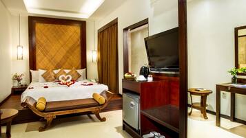 A hotel room with a bed, a television, a desk, and a small table.
