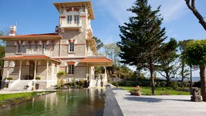 Un grand bâtiment en pierre, à plusieurs étages, doté d’une cour intérieure et d’un élément décoratif aquatique.