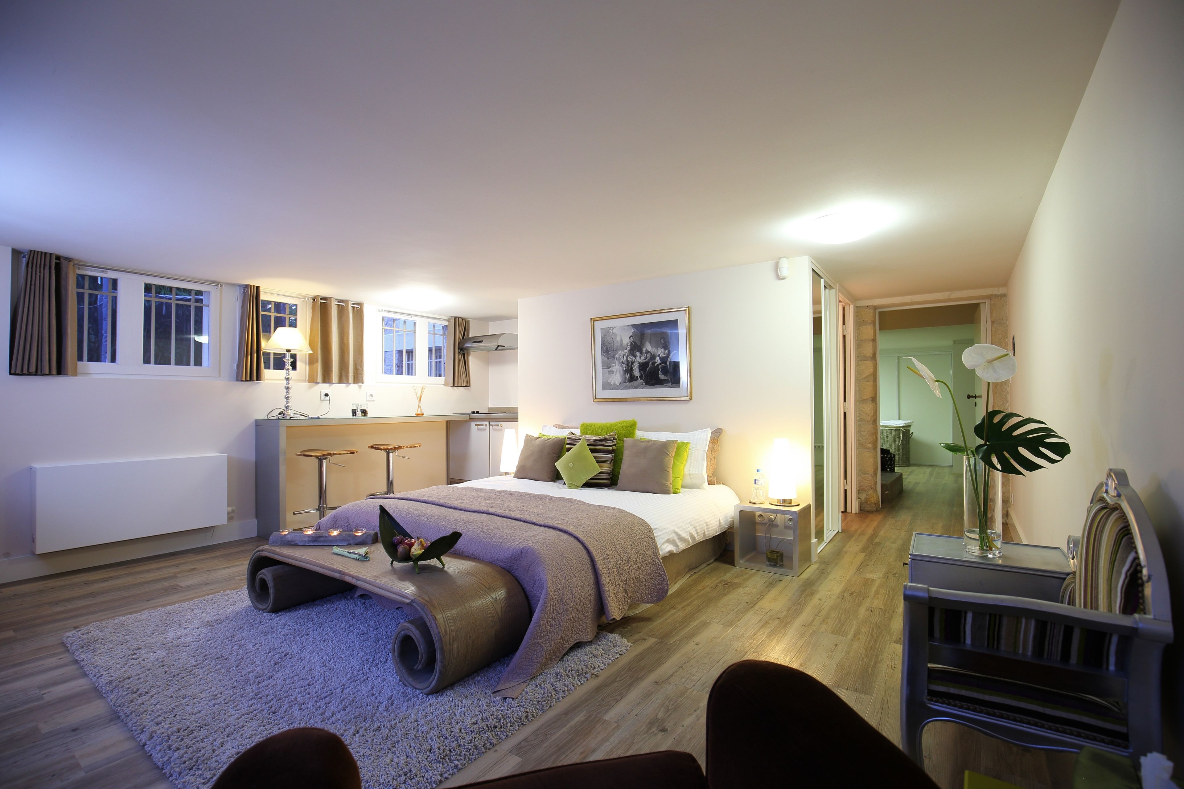 Une chambre à coucher moderne, avec un lit, une table de chevet, une lampe et une grande fenêtre.