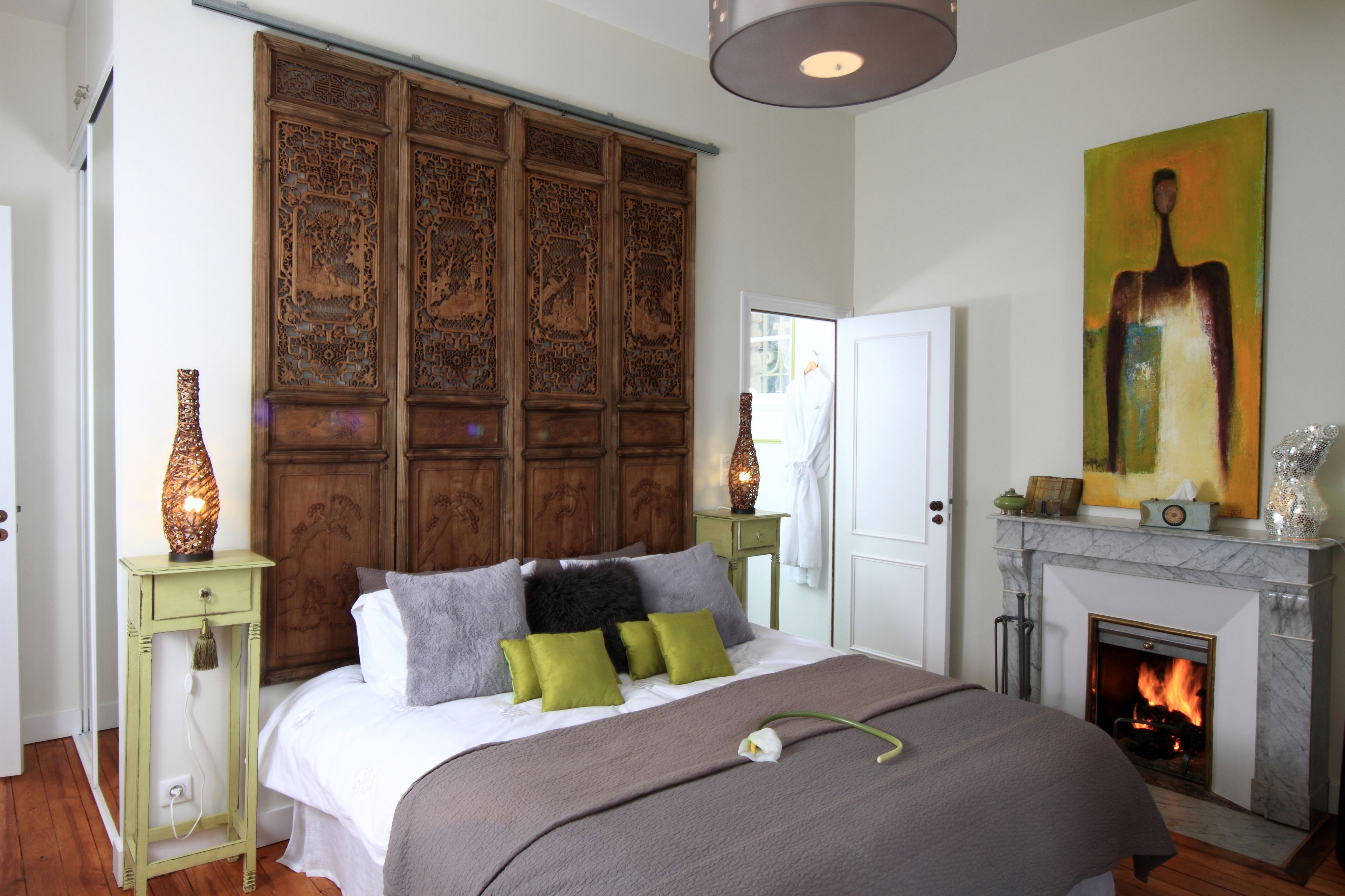 A bedroom with a large bed, a wooden headboard, a fireplace, and a painting on the wall.