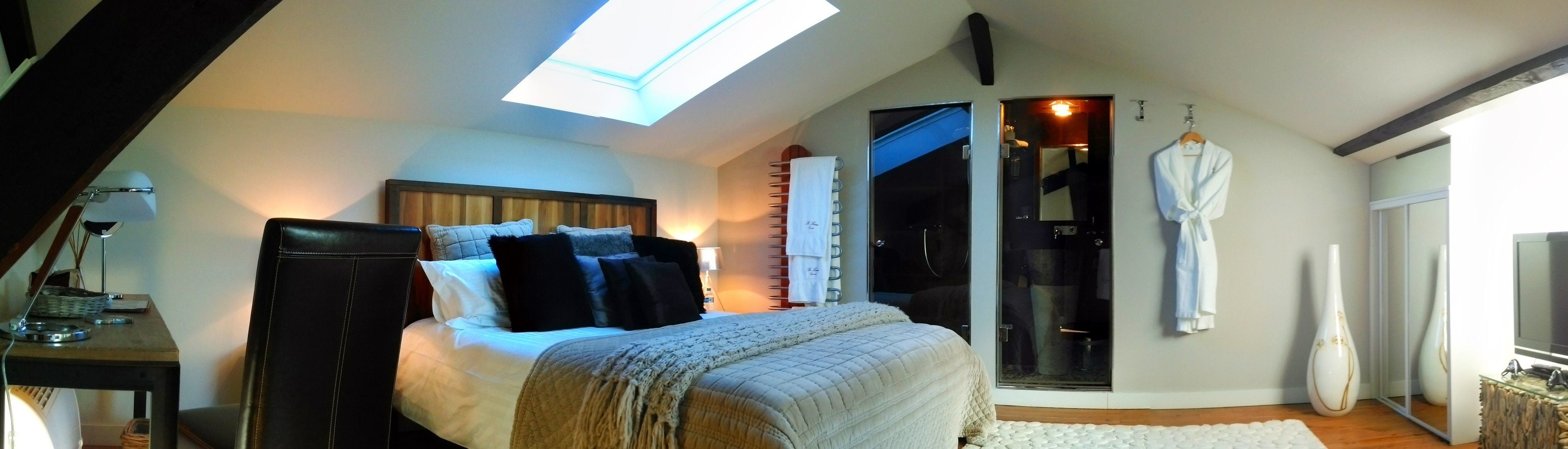 Une chambre à coucher comprenant un lit, une table de chevet, une lampe, une fenêtre et une porte-fenêtre coulissante donnant sur une salle de bain.
