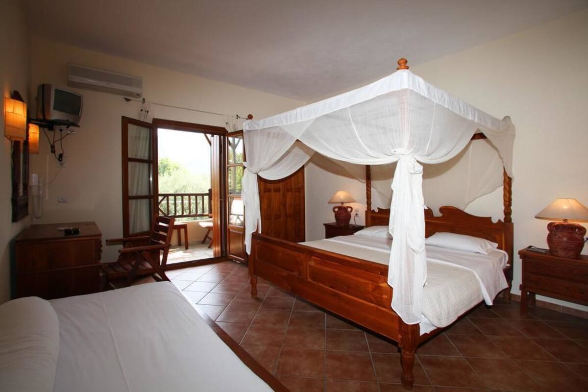 A bedroom with a four-poster bed, a wooden nightstand, a desk, and a chair.